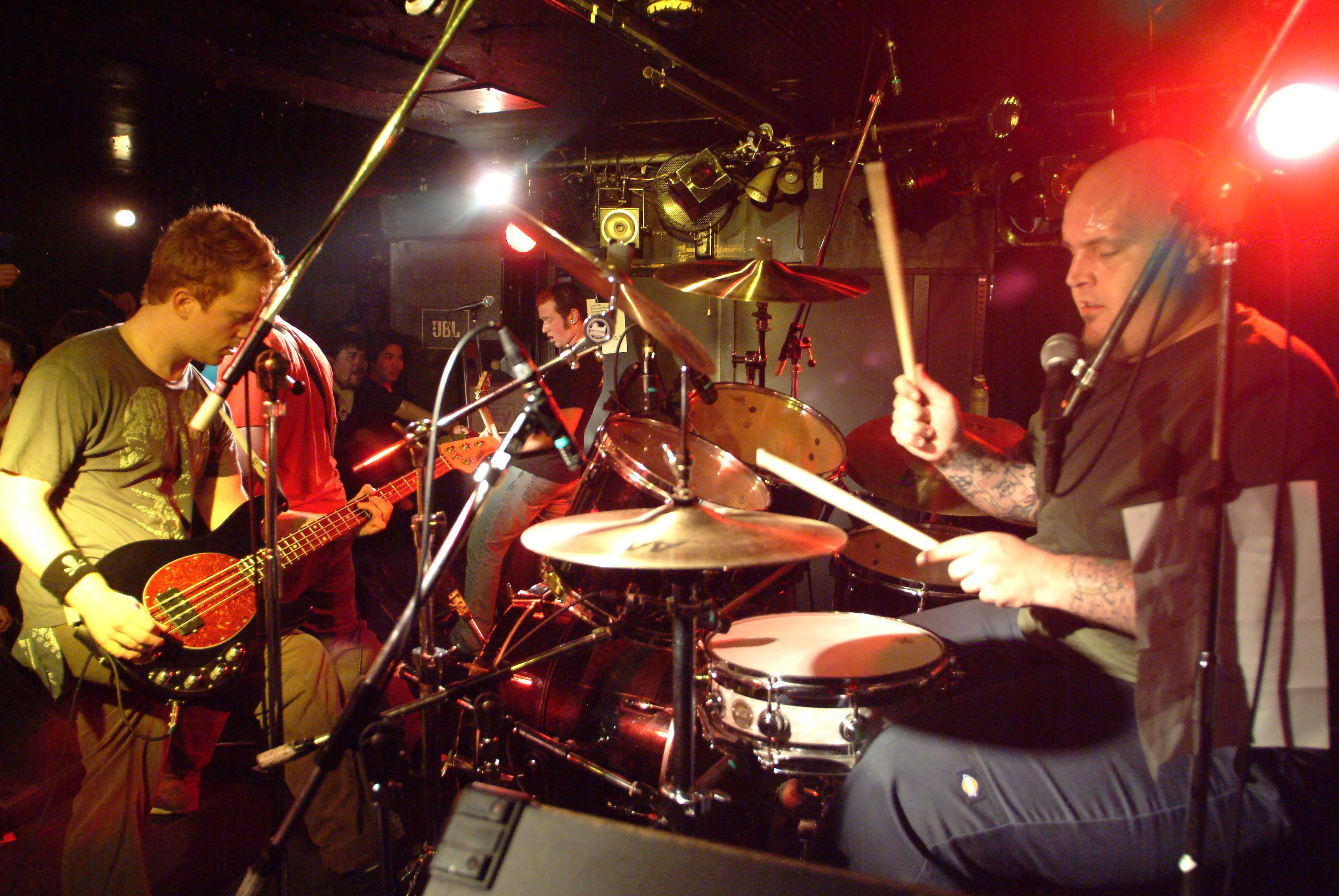 Close-up of the SecondShot bassist and drummer mid-song under red stage lights