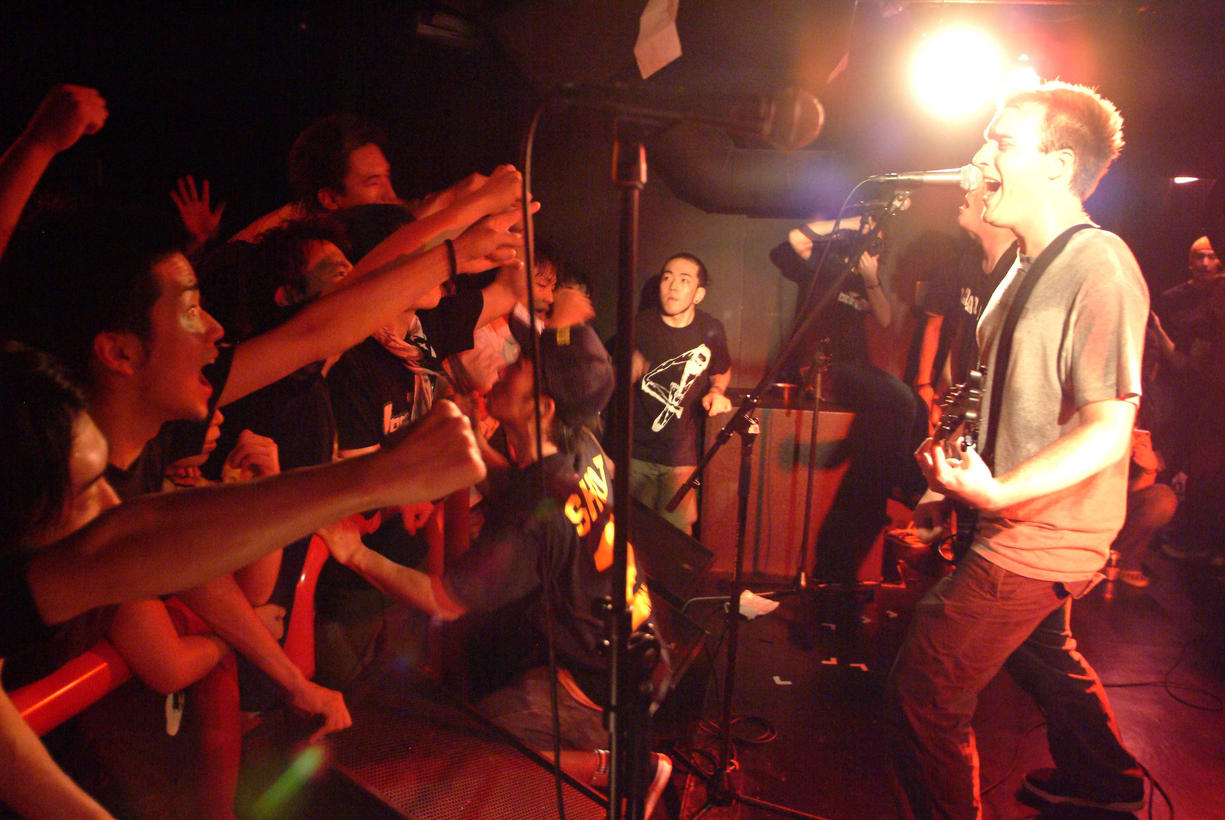 SecondShot guitarist shouting into the mic as fans reach toward the stage