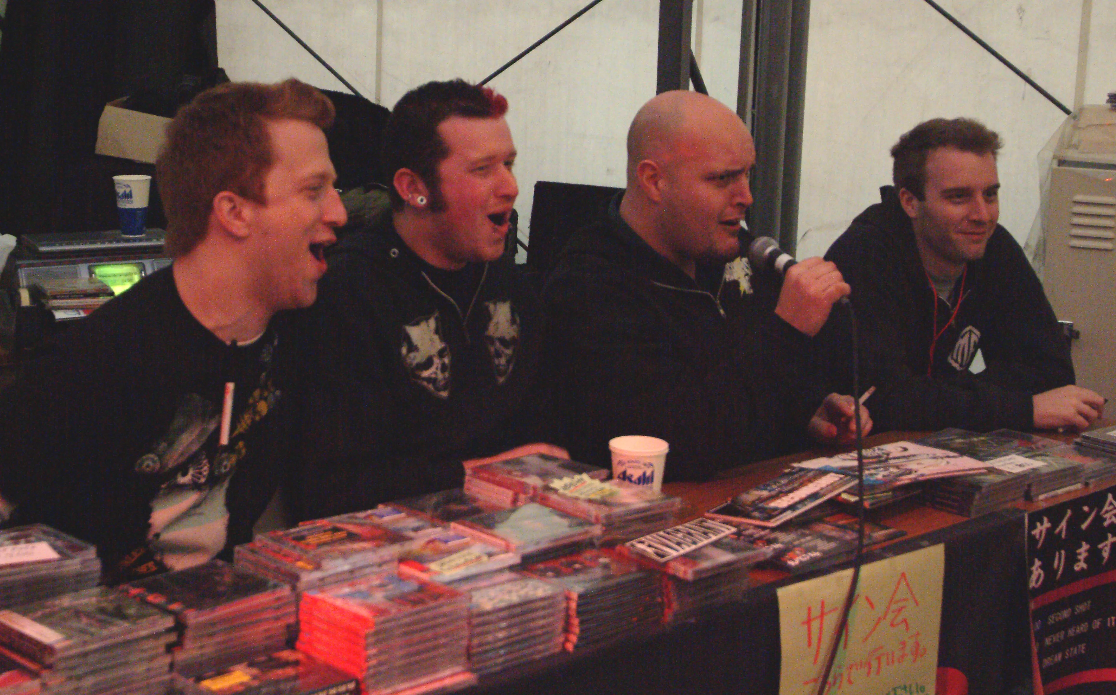 SecondShot members singing along and laughing at the merch table