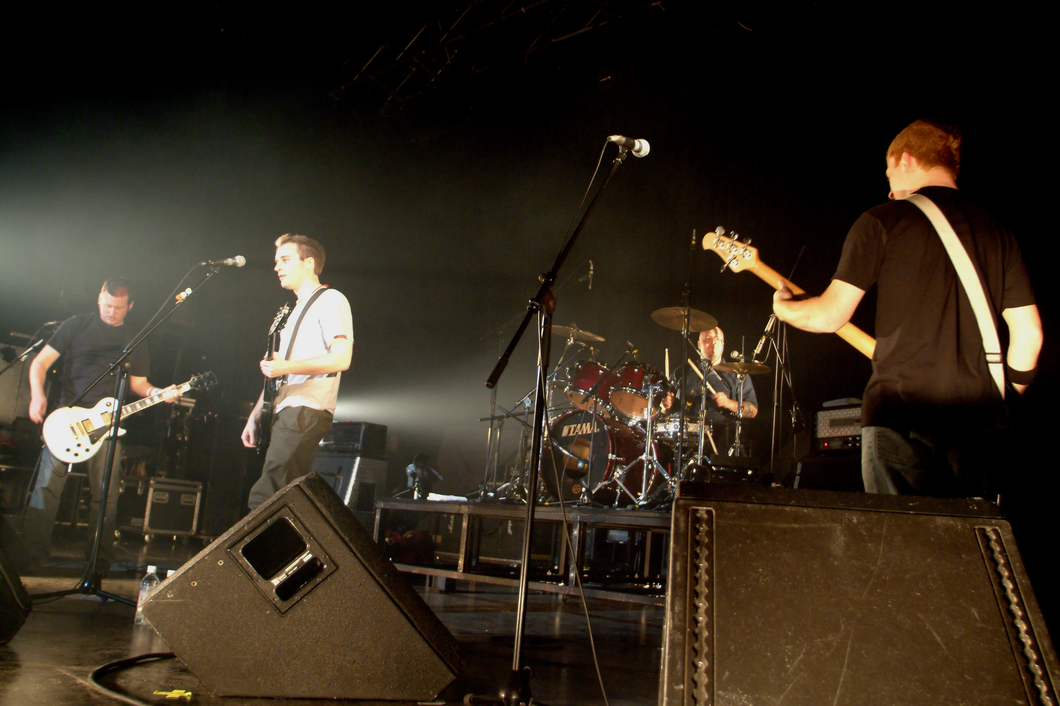 Wide shot of SecondShot playing a large stage, drummer in the background