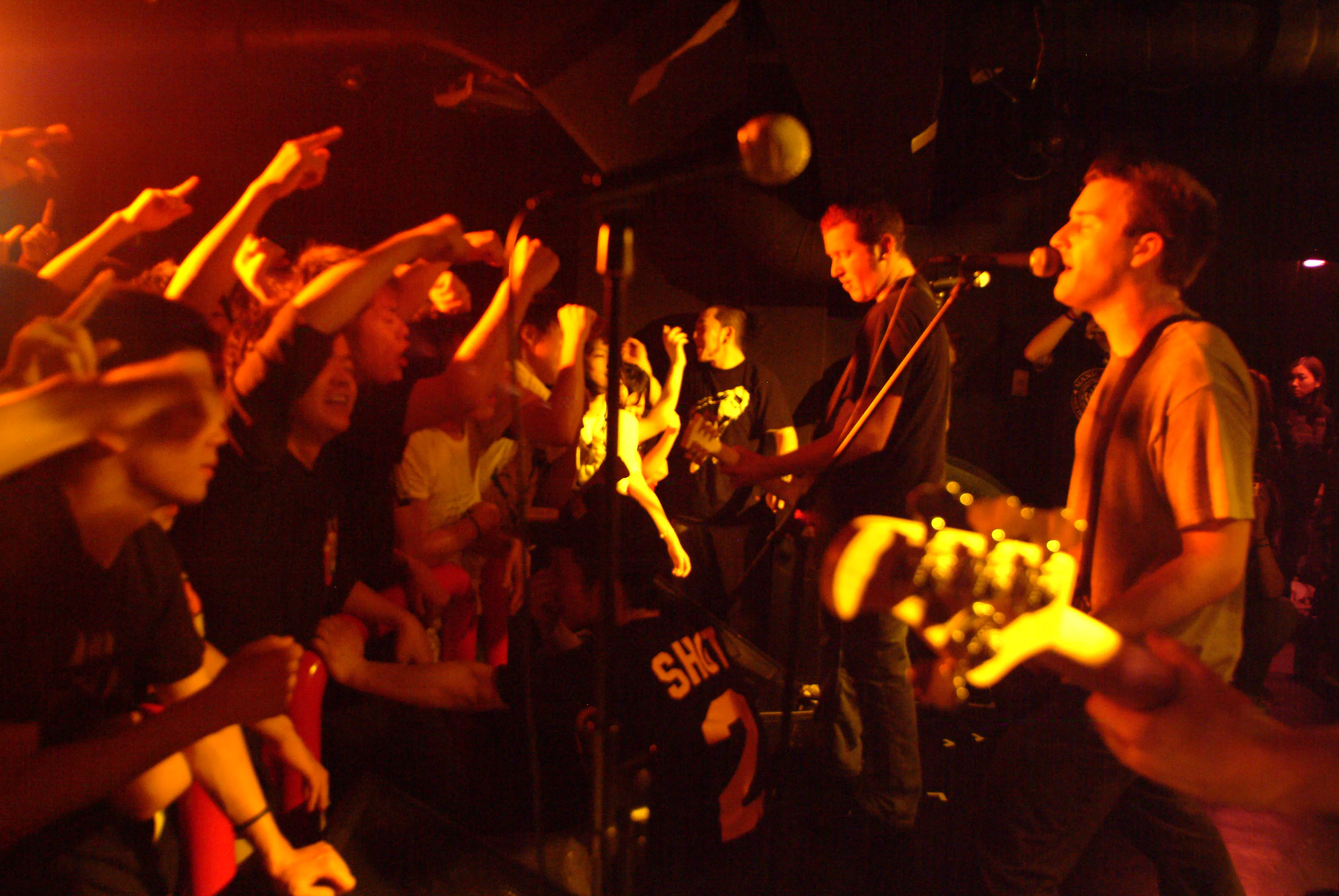 SecondShot singer in warm orange light with fans reaching out from the front row