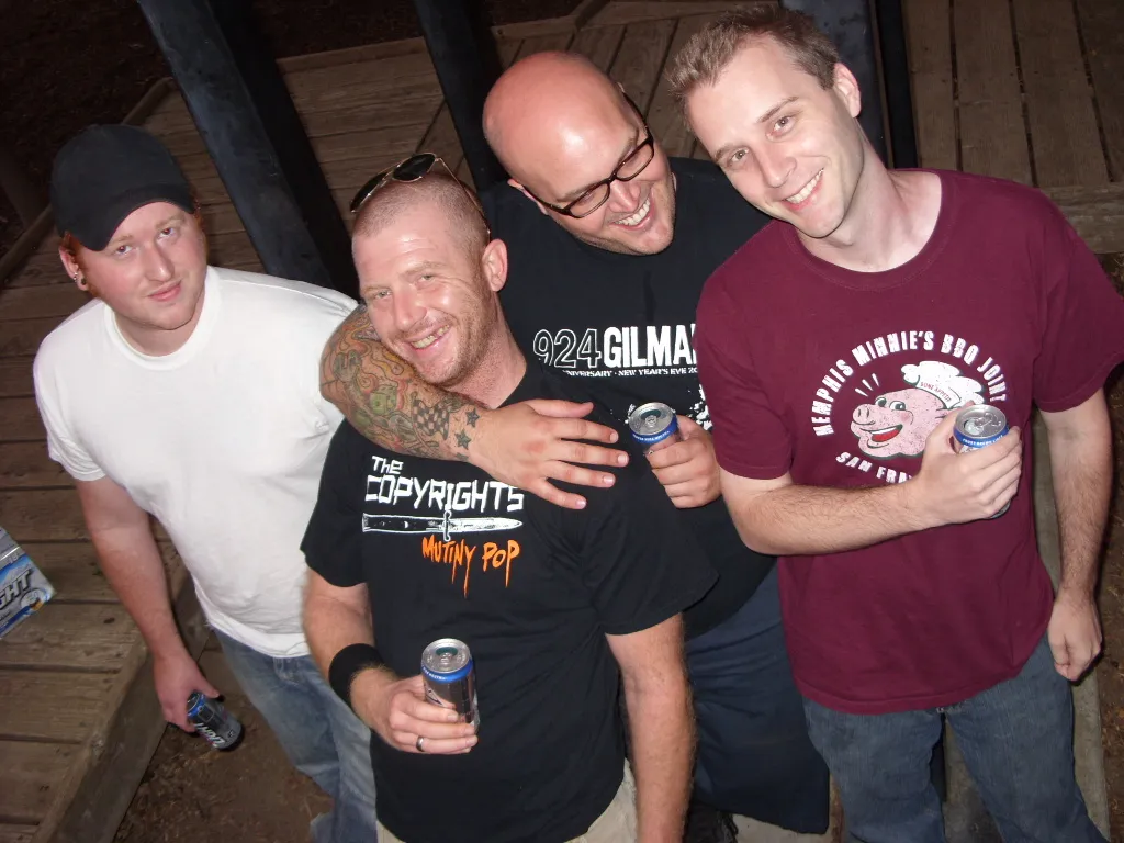 Four SecondShot members smiling for the camera on a wooden deck, holding drinks